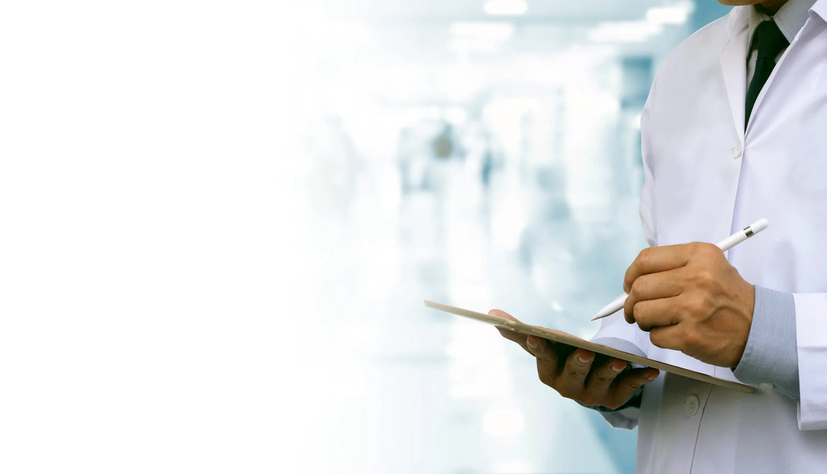 Clinician in a white lab coat using a tablet in a medical research setting